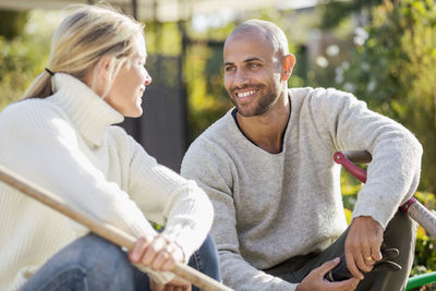 Mature couple with gardening equipment sitting at yard