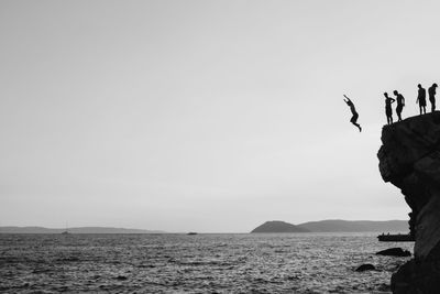 People diving in sea against clear sky