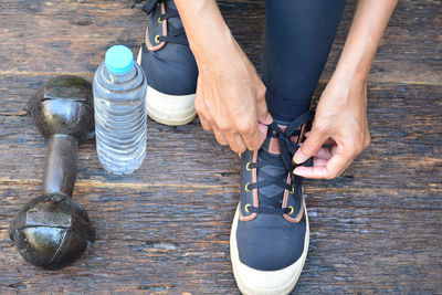 Low section of woman tying shoelace on table