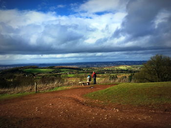 Rear view of man walking on agricultural field against sky