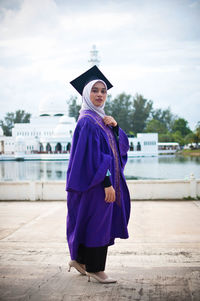 Portrait of a smiling young woman standing against built structure