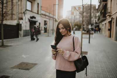 Young woman using smart phone on city street