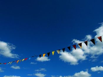 Low angle view of multi colored bunting flags against blue sky