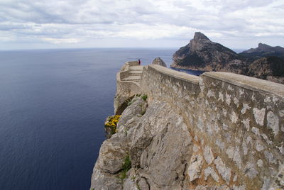 Scenic view of sea by cliff against sky