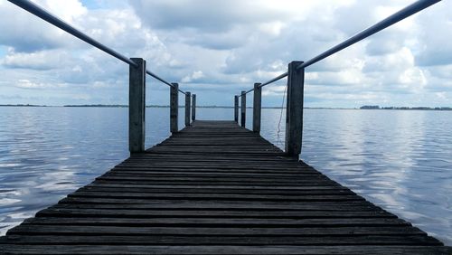 Empty pier over sea against sky