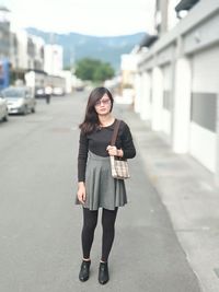 Portrait of young woman standing on road