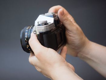 Close-up of hand holding camera against black background