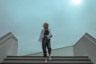 Low angle view of woman walking on staircase against sky