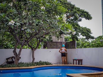 Woman taking shower by poolside against trees