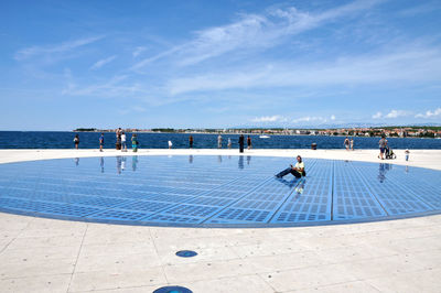 People enjoying in water against blue sky