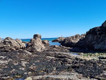 Rocks on beach against clear blue sky