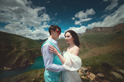 Side view of young couple standing against mountain
