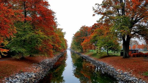 Canal amidst trees against sky during autumn
