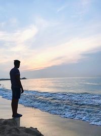 Man standing on beach against sky during sunset