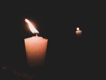 Close-up of lit candle against black background