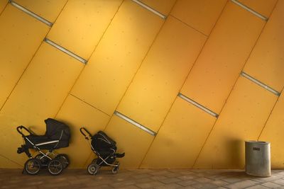 Baby carriage against yellow wall