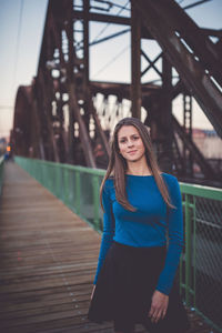 Beautiful young woman with long healthy dark blonde hair in blue long sleeve shirt and black skirt