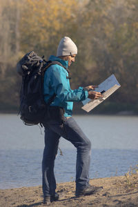 Portrait of traveler man at lake in autumn with a map