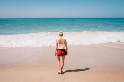 Rear view of woman walking on shore at beach