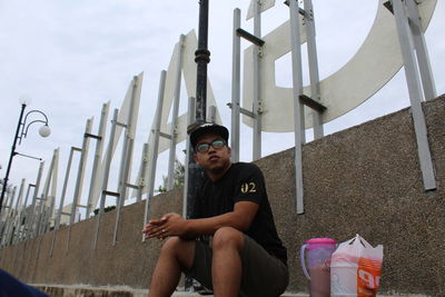 Portrait of young man sitting against sky