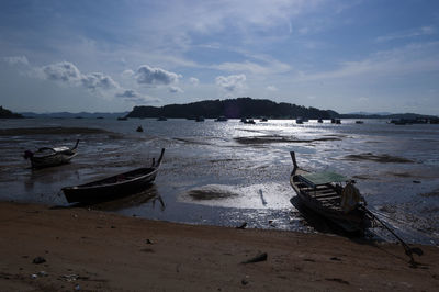 Boats moored on shore against sky