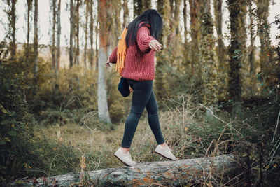 Full length of woman standing amidst trees in forest