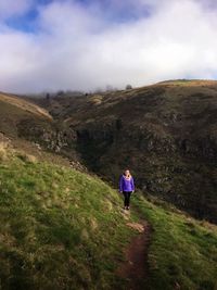 Full length of woman standing on mountain road against sky