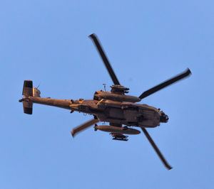 Low angle view of military helicopter flying against clear blue sky