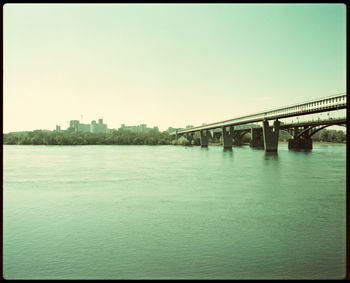 Bridge over calm river against clear sky