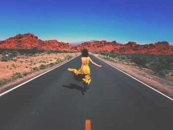 Rear view of woman riding motorcycle on road against sky