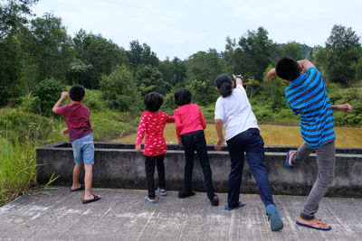 Rear view of boys playing on landscape against sky