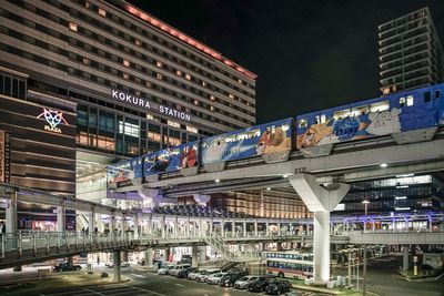 Illuminated bridge by buildings in city at night