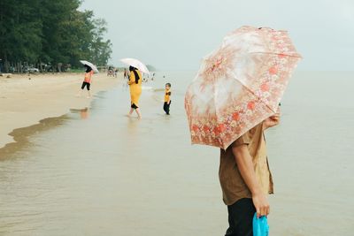 People walking on wet beach during rainy season