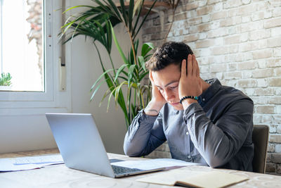 Side view of young man using laptop at office