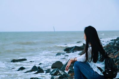 Woman looking at sea against clear sky
