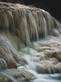 Scenic waterfall smooth stream with sunlight hitting tides. erawan falls, kanchanaburi, thailand.