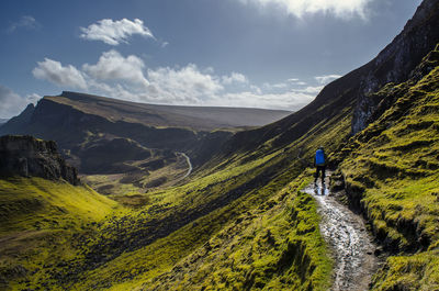 Rear view of man walking on mountain against sky