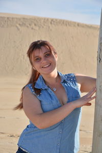 Portrait of young woman standing by tree trunk