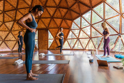 Full body side view of happy women preparing to practice yoga in light studio