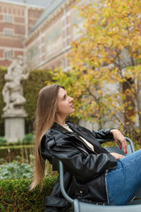 A beautiful woman is relaxing in a cozy armchair in a beautiful autumn park somewhere in europe.