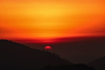 Silhouette of mountain against orange sky