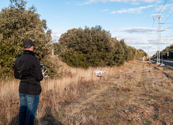 Rear view of man on field against sky