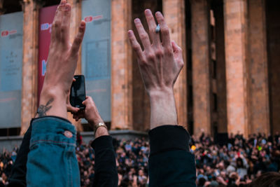 Cropped hands of audience arms raised in city