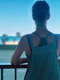 Rear view of woman looking at swimming pool against sky