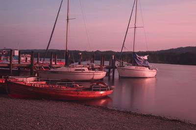 Sailboats moored in marina at sunset