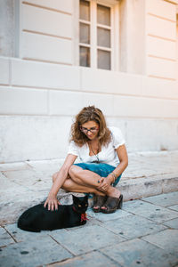 Full length portrait of young woman sitting outdoors