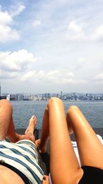 Low section of woman relaxing on sea against sky