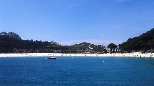 Sailboats moored on sea against clear blue sky