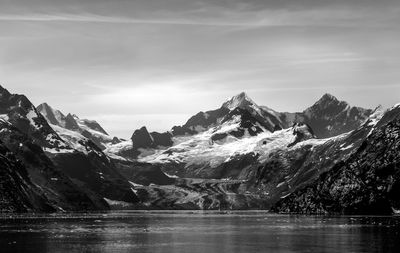 Scenic view of lake by snowcapped mountains against sky