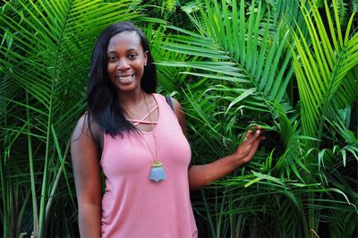 Portrait of smiling woman standing against plants